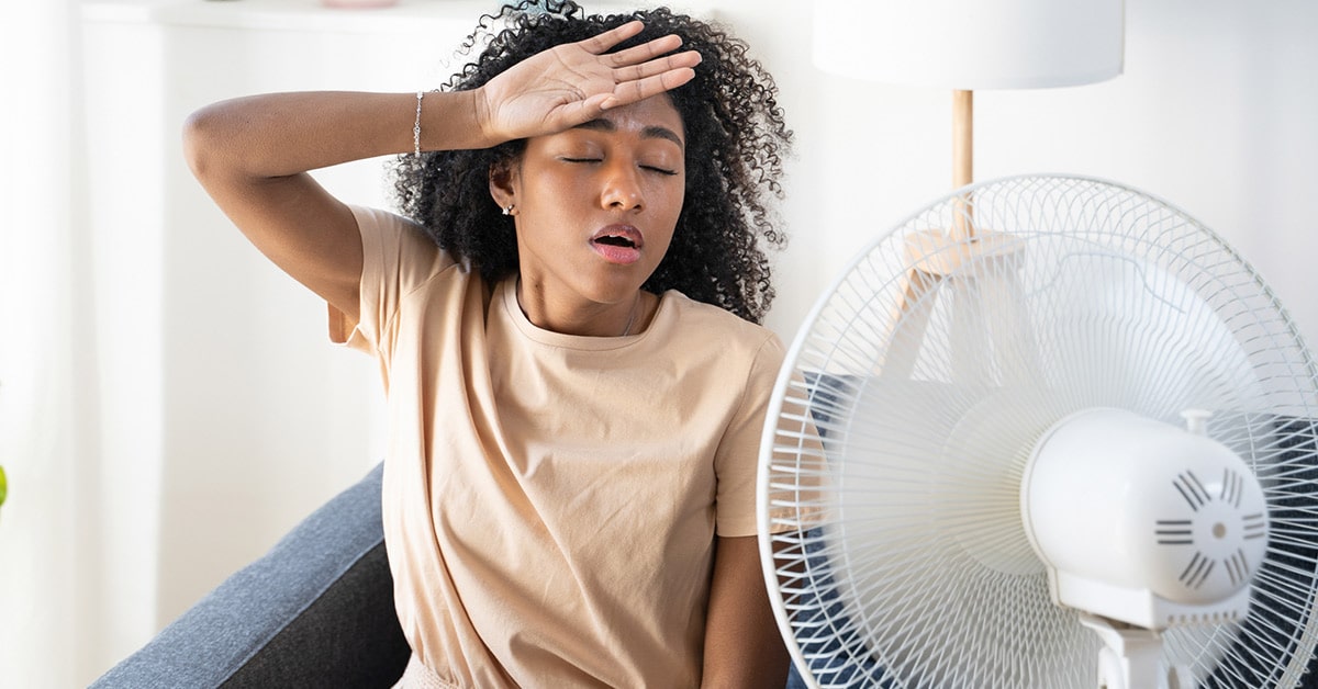 woman cooling off in front of fan